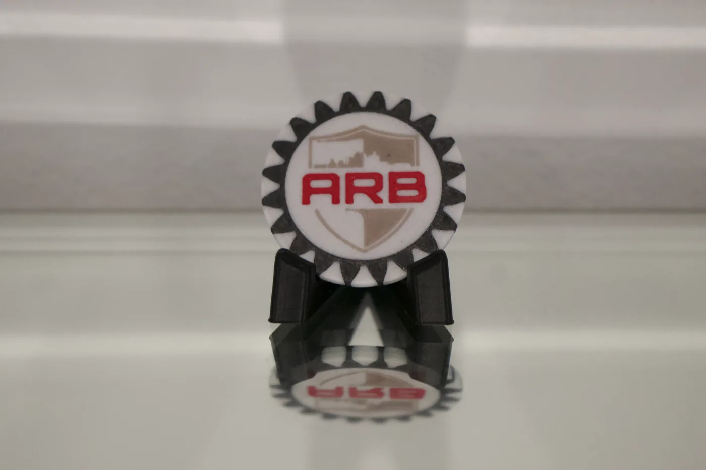 ARB branded challenge coin on display stand